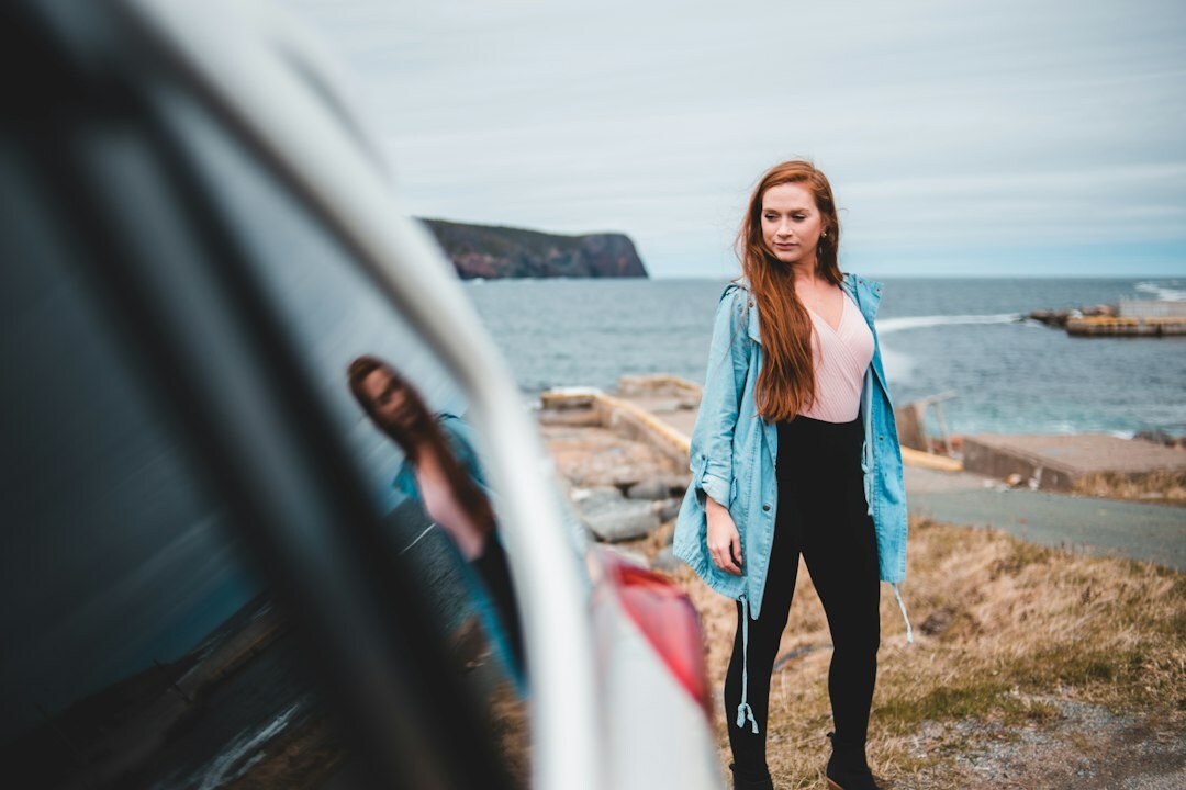 Young woman holding car keys next to a rental car outside