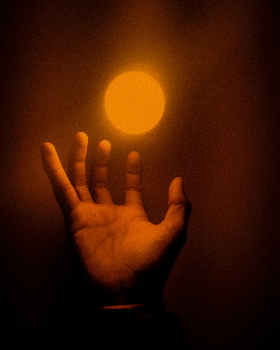 Hand reaching toward a glowing lightbulb idea concept